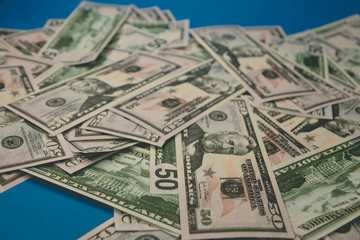 scattered dollar bills close-up. fifty dollars blue background