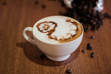 Coffee latte with beautiful design on top, coffee beans background