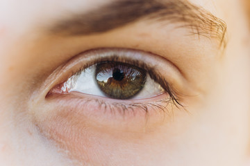 Obraz premium looking young boy looking straight. Cropped portrait of a Caucasian man in the sun. open eye close up