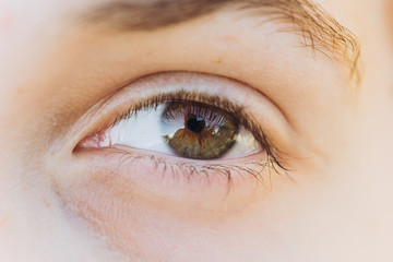 Obraz premium looking young boy looking straight. Cropped portrait of a Caucasian man in the sun. open eye close up