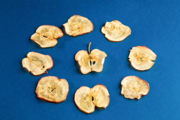Healthy apple chips laid out in circle on blue background.
