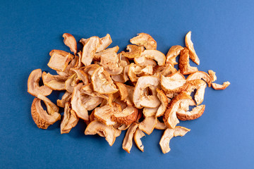 Chaotic bunch of dried apple slices on blue background.