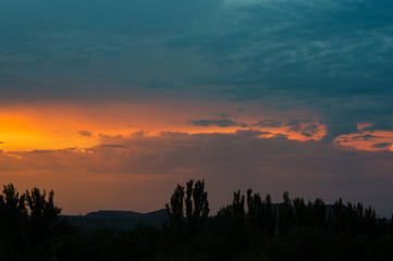 Landscape with dramatic light - beautiful golden sunset with saturated sky and clouds.