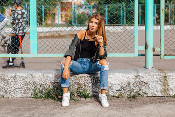 Fashion portrait of trendy young woman wearing sunglasses, and bomber jacket sitting next to rabitz...