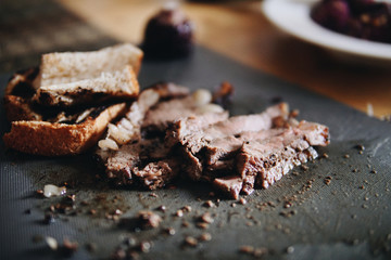 Blurred roast beef, corn, bread served on the table.