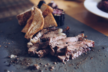 Blurred roast beef, corn, bread served on the table.