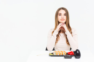 Young beautiful girl preparing for  eats sushi rolls with chopsticks on a white background portrait.