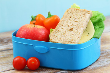 Healthy, nutritious school lunchbox  containing brown cheese sandwich, crunchy yellow pepper and red apple