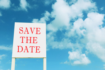 sign against blue sky with clouds with the text save the date