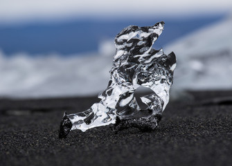 Amazing transparent blue iceberg pieces on Diamond beach with black sand near Jokulsarlon lagoon, Iceland. Ice calving. Black and white contrast.