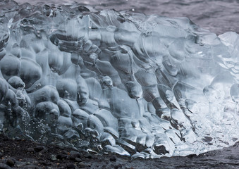 Obraz premium Amazing transparent blue iceberg pieces on Diamond beach with black sand near Jokulsarlon lagoon, Iceland. Ice calving. Black and white contrast.