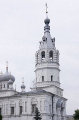 Christian orthodox white church with silver and grey domes with gold crosses. Calm grey sky above