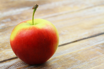 Red and yellow apple on wooden surface with copy space