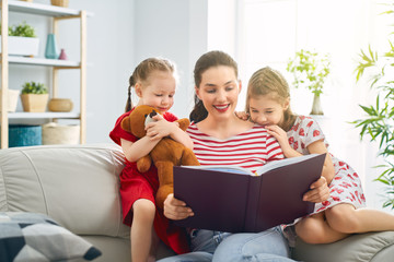 mother reading a book to daughters