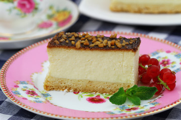 Slice of delicious baked cheesecake with chocolate topping sprinkled with nuts