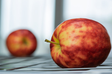 Ripe, colorful mottled apples on a grate and background of a bright window.
