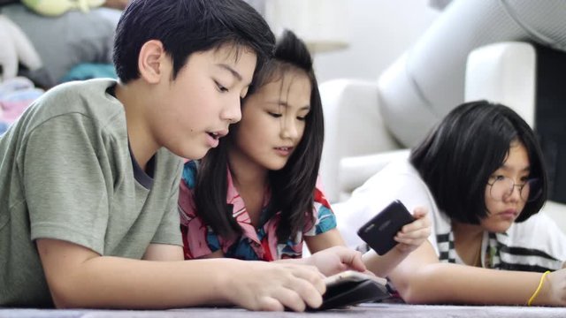 Child playing tablet or smartphone at home , Asian boy and girl playing game on mobile phone together with smile face.