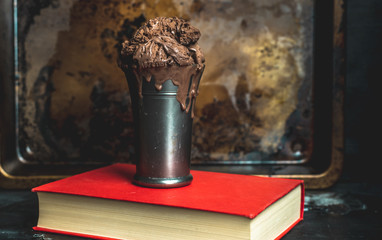 chocolate ice cream in an old metal mug on a dark metal gloss background