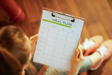 Closeup on sports woman with clipboard filling meal plan