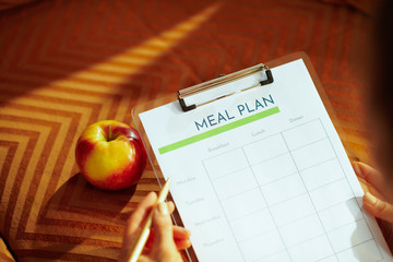 Closeup on female hands holding clipboard with meal plan