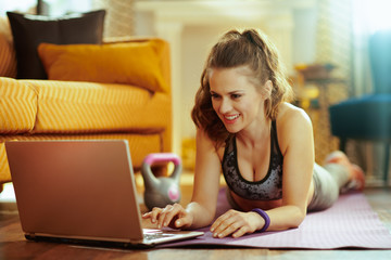 sports woman watching fitness videos on internet via laptop