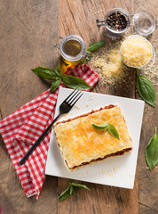Lasagna close-up. Background in soft and warm colors, decorated with elegant red and white fabrics.