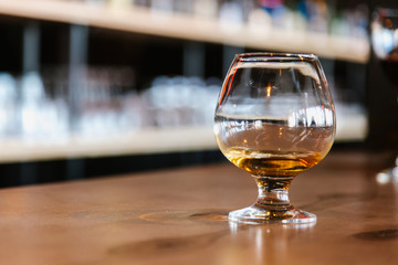 An unfinished glass of whiskey (cognac)  is on the bar. After party. With Copy space