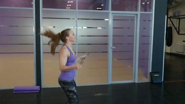 Energetic fitness girl jumping a skipping rope in fitness wellness studio gym.