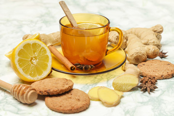 A yellow cup of tea, with ginger roots, lemon and spices. A healthy lifestyle, anti-flu and anti-inflammatory concept.
