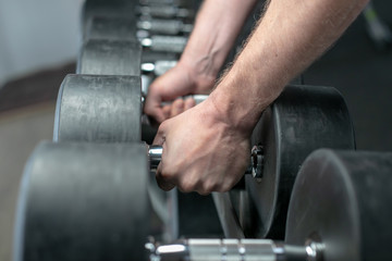 Colorful images. Hands holding dumbbells in the gym.