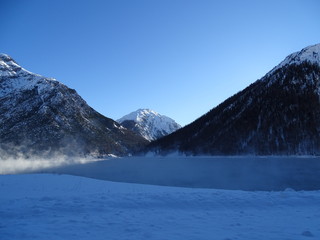 lago di livigno in inverno prima del congelamento coperto di vapore al mattino presto 