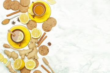 Ginger tea in a cup with ginger roots and lemon on marble textured background, top view. A healthy lifestyle, anti-flu and anti-inflammatory concept.