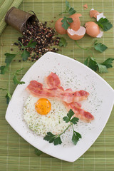 Close-up of delicious fried egg breakfast with bacon. With warm green background.