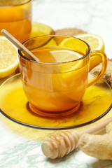 A yellow cup of tea, with ginger roots, lemon and spices. A healthy lifestyle, anti-flu and anti-inflammatory concept.