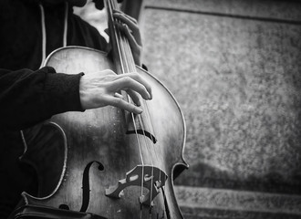 Street musician or busker playing upright bass in urban city environment.
