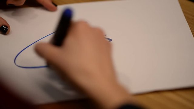 The hand of a young girl encircles the inscription Paris with a blue marker.