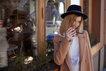 Happy young blond woman in a stylish hat and coat