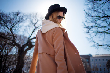 Happy young blond woman in a stylish hat and coat