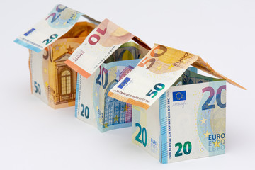 Trois maisons faites en billets de 10, 20, et 50 euros, avec quelques pièces de monnaie