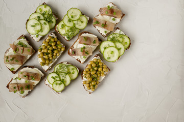 sandwich with salted fish, cucumber and green peas on a light background and greens on a gray background.