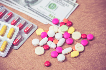 many color of pills and dollars bank note on wood background