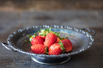 Fresh strawberry in antique metal plate on wooden table