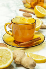 A yellow cup of tea, with ginger roots, lemon and spices. A healthy lifestyle, anti-flu and anti-inflammatory concept.