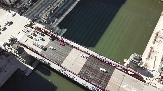 AERIAL: watching a fire truck pass over a bridge over a river in the city of Chicago, Illinois during the St. Patrick's Day Parade.