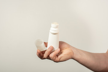 Male hands holding deodorant for armpits on a white background
