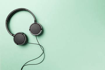 Headphones on Mint background. Black headphones on a pastel background. Top view. Flat lay. Copy space. Minimal style with colorful paper backdrop. Music concept. Neo Mint color of the year 2020