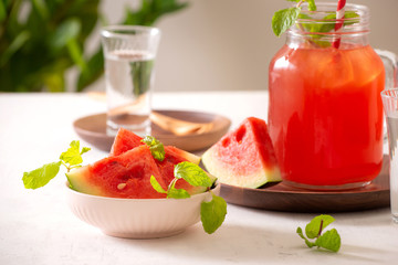 Watermelon drink in glass with slices of watermelon on whitebackground