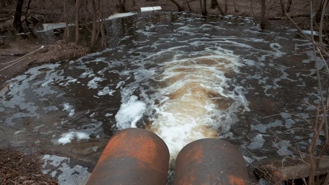Discharge of sewage into a river. Dirty sewage from the pipe, environmental pollution.