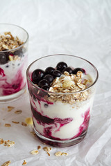 Ice cream with berries and muesli. Ice cream in a glass with currants, berry jam and muesli on a white background. Close-up. 