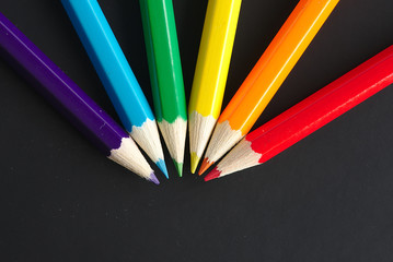 Fototapeta premium six crayons de couleur arc en ciel sur une feuille noire avec espace pour du texte